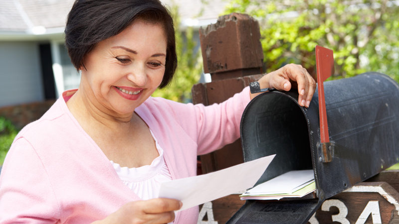 Senior woman opening a direct mail piece.
