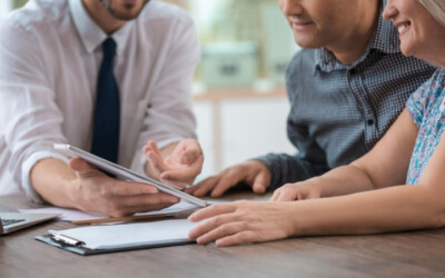 An image of an insurance agent displaying options to an elderly couple, with a tablet.