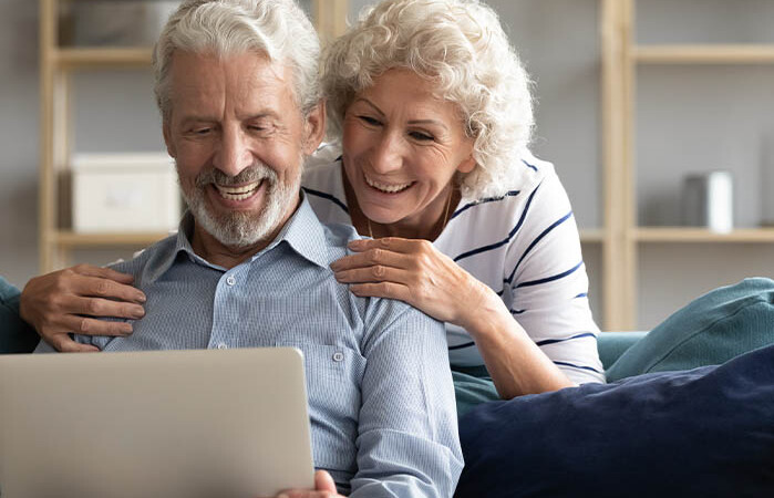 Elderly couple reviewing insurance options online.