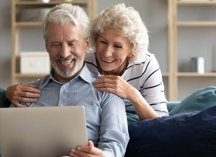 Elderly couple reviewing insurance options online.