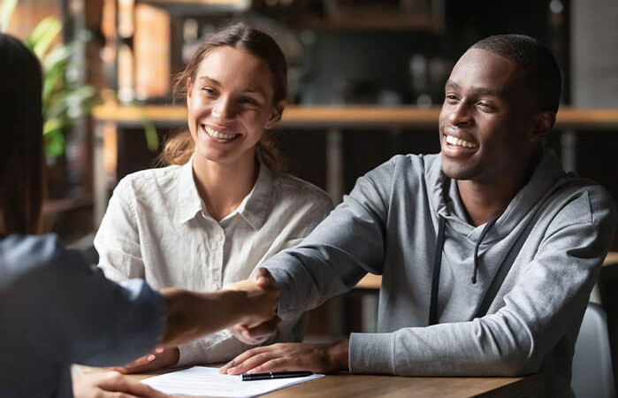 An image of an insurance agent shaking hands with some satisfied clients.