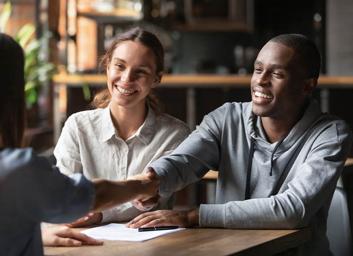 An image of an insurance agent shaking hands with some satisfied clients.