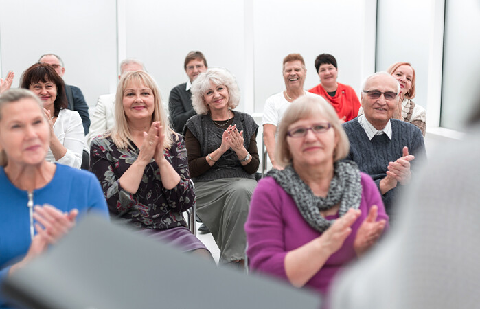 Seminar audience clapping together for host.