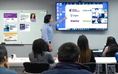 Man pointing at screen, discussing direct mail branding, with crowd watching.