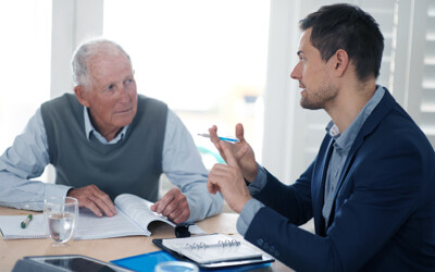 A finance planning professional speaking with an elderly client.