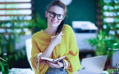Youthful and energetic female insurance agent speaking on the phone with new clients to set an appointment to sell them an insurance policy after running an exclusive marketing campaign for AEP.