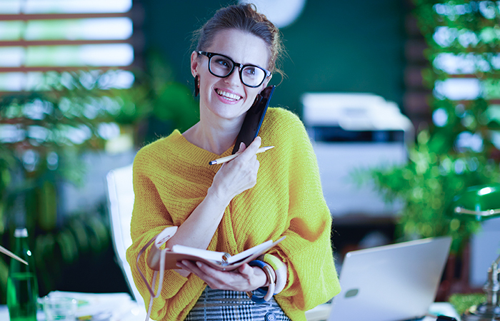 Youthful and energetic female insurance agent speaking on the phone with new clients to set an appointment to sell them an insurance policy after running an exclusive marketing campaign for AEP.