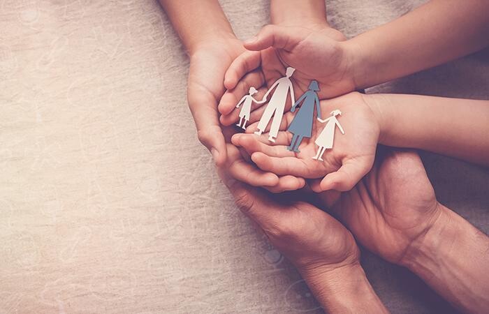 Set of three hands holding a paper family, preparing for a funeral.