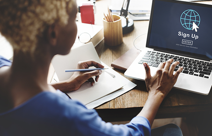 A female registered social security analyst working on a laptop while taking notes.