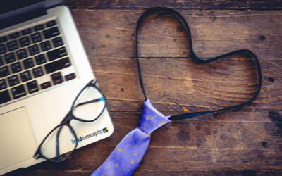 Image of half of a laptop, a pair of glasses, and a tie in the shape of a heart, with Lead Concepts iconography on the tie.
