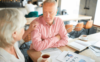 Senior couple discussing retirement planning over coffee with financial documents and charts on the table