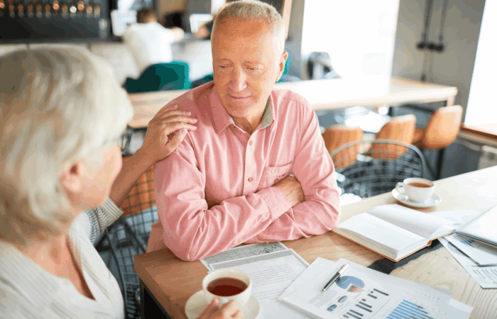Senior couple discussing retirement planning over coffee with financial documents and charts on the table