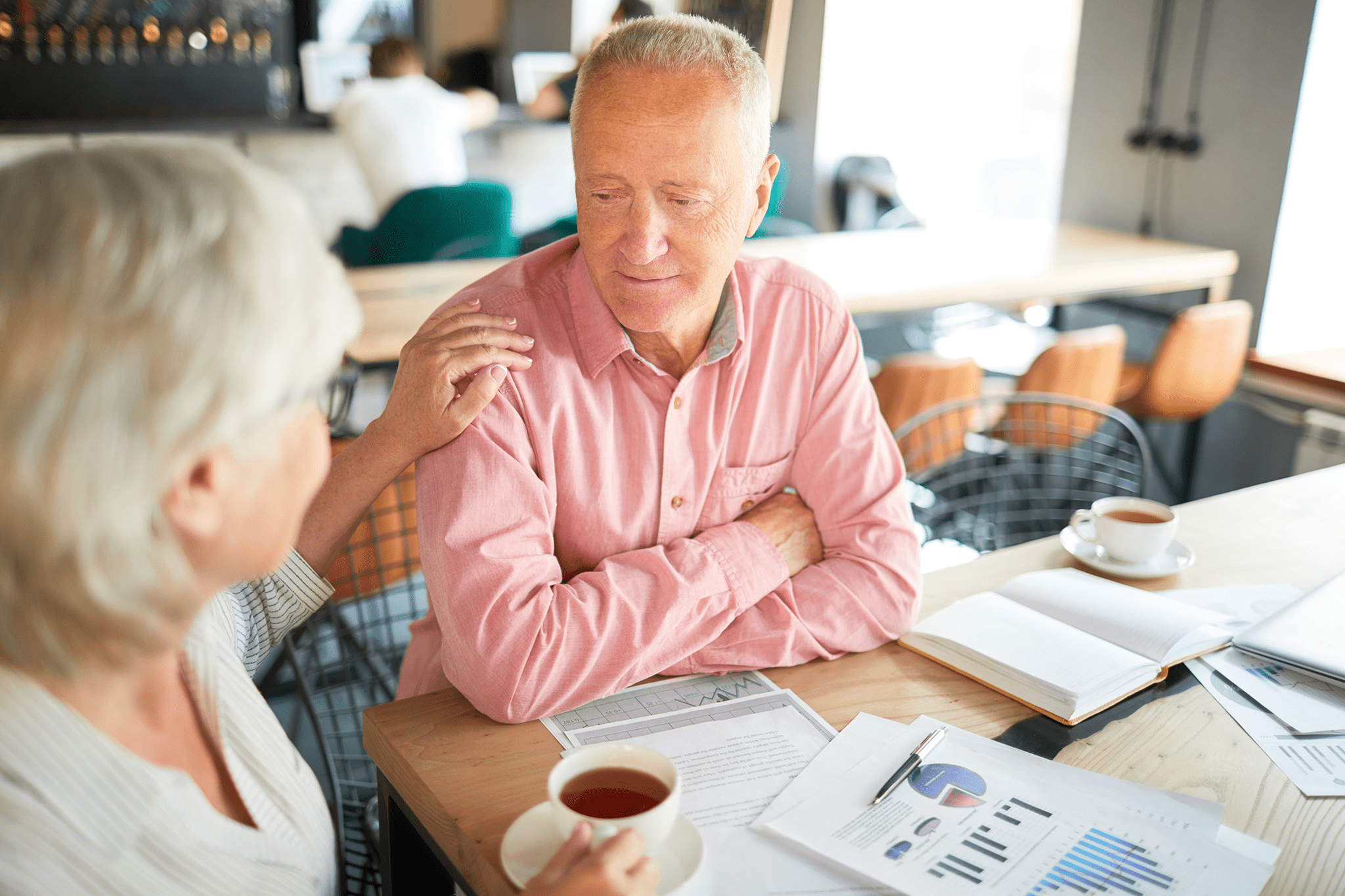 Senior couple discussing retirement planning over coffee with financial documents and charts on the table
